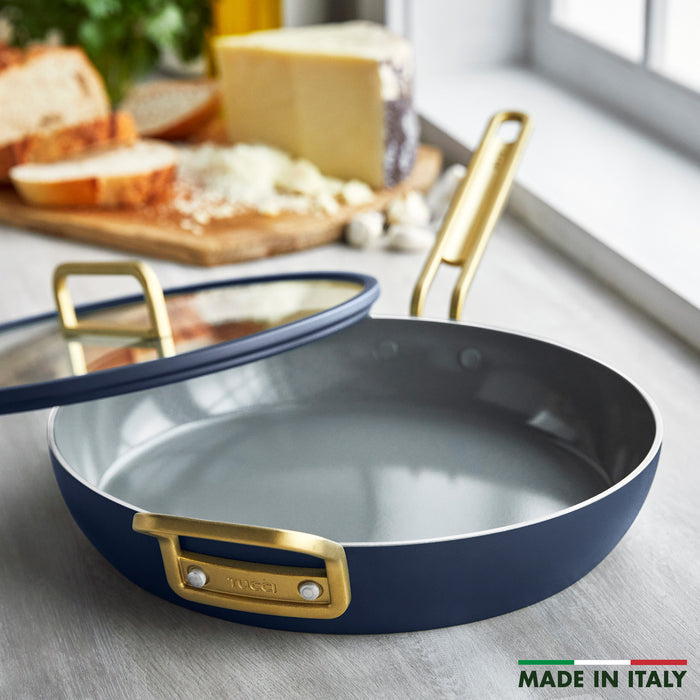 Blue frypan with gold handles on counter beside bread, cheese, and garlic; 12-inch size visible.