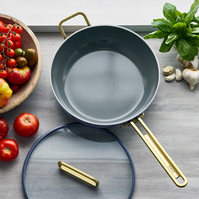 Marino blue 4.5-qt pan with gold handle and lid, tomatoes and basil beside it.