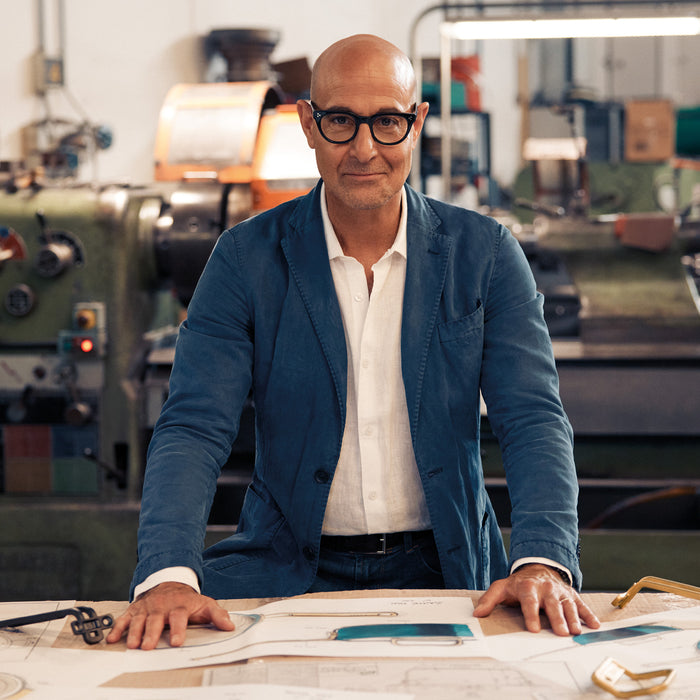 Man in glasses and blue jacket examines a Stanley Tucci 8-inch Marino Blue frypan in an industrial workshop.