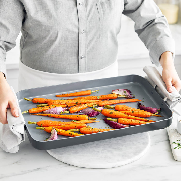Baking tray of seasoned carrots and red onions prepared beside a Valencia Pro Ceramic Nonstick Griddle.