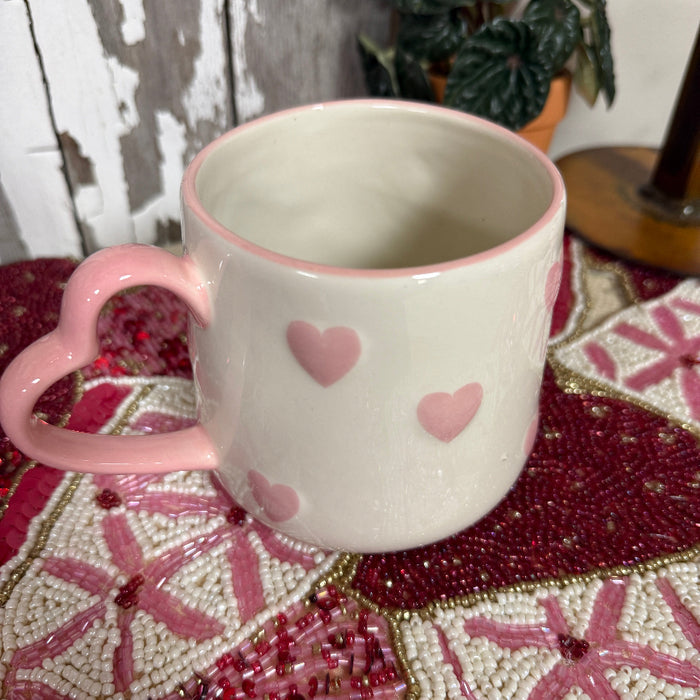 Pink mug with heart designs on a decorative surface