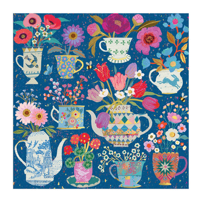The Victoria Ball Potted Teacups 500 Piece Foil Puzzle features colorful teapots and teacups brimming with bright flowers, set on a blue textured background with vibrant floral and geometric patterns. Brand: Victoria Ball.