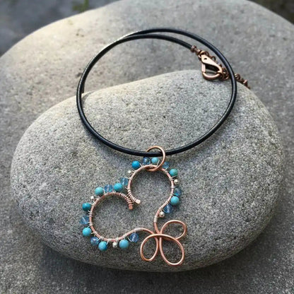 Wire Wrapped Copper Turquoise Heart Infinity Charm Necklace on a stone background