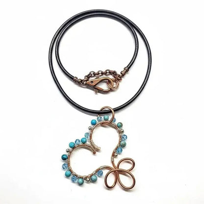 Wire Wrapped Copper Turquoise Heart Infinity Charm Necklace featuring turquoise beads and black leather chain.