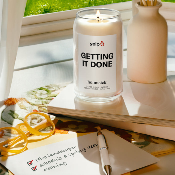 A lit Getting It Done candle next to a completed list of chores